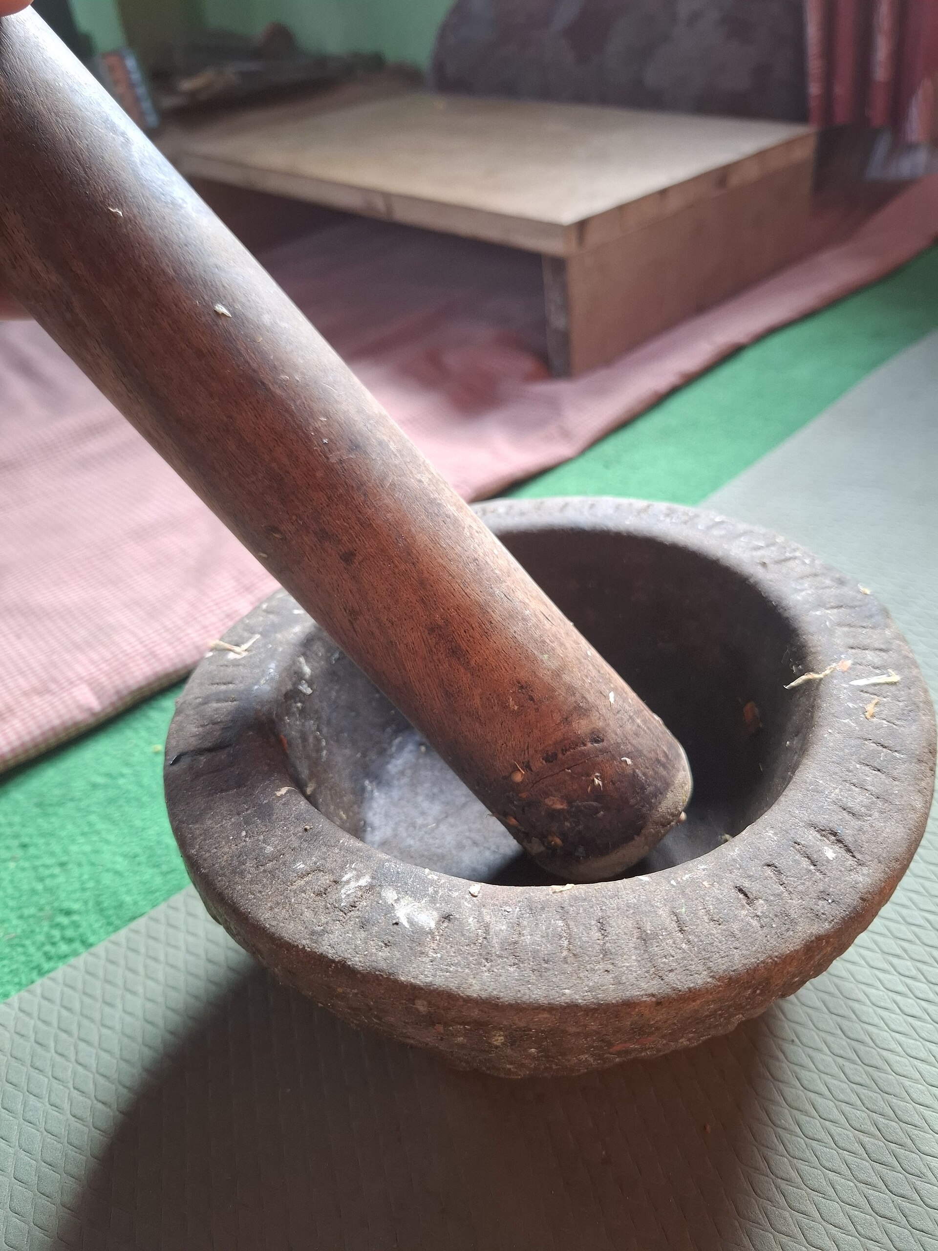 Whole spices beside a wooden mortar and pestle