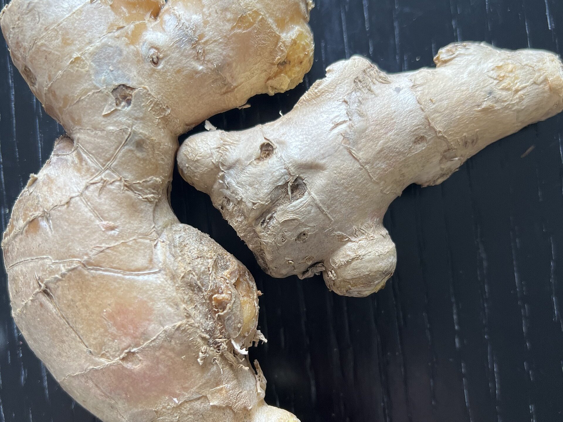 Fresh ginger rhizomes on dark ebony wood