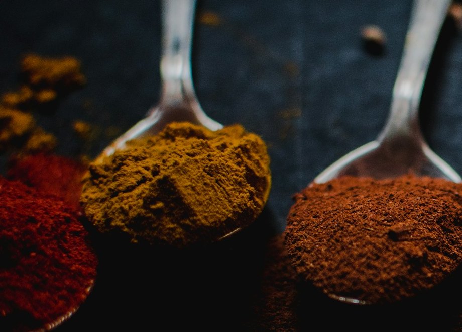 A spoon mounded with golden turmeric powder on dark slate
